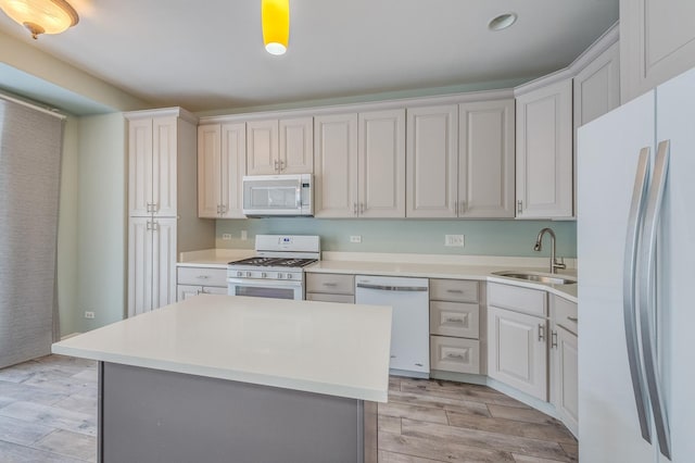 kitchen with white appliances, light countertops, light wood-type flooring, and a sink