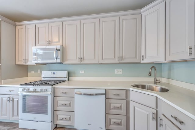 kitchen featuring white appliances, light countertops, and a sink