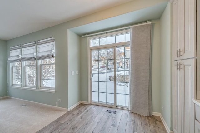 doorway with visible vents, baseboards, and light wood finished floors