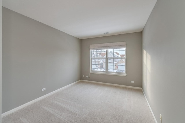 empty room featuring visible vents, baseboards, and light carpet