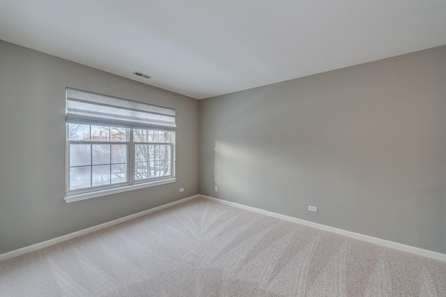 empty room with carpet, visible vents, and baseboards