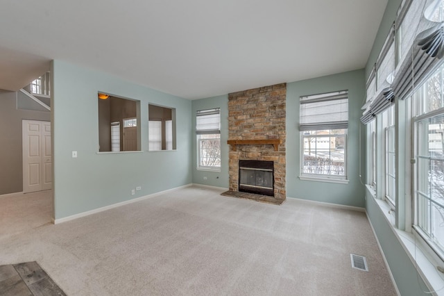 unfurnished living room featuring baseboards, visible vents, light carpet, and a stone fireplace