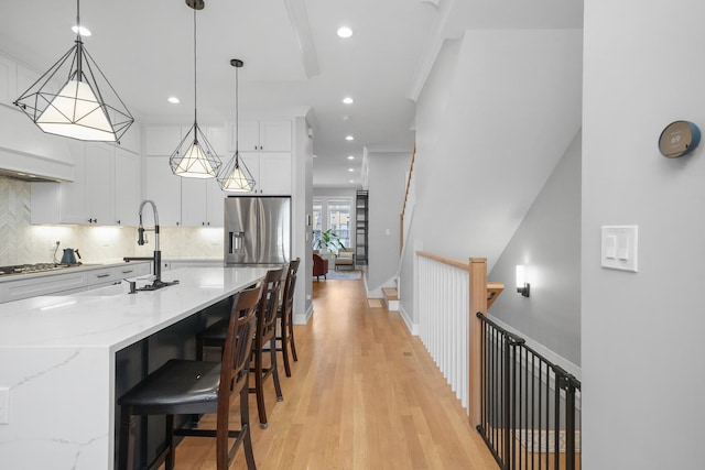 kitchen with light stone counters, light wood-style flooring, white cabinets, appliances with stainless steel finishes, and backsplash