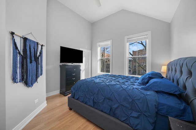 bedroom featuring a ceiling fan, vaulted ceiling, light wood-style floors, and baseboards