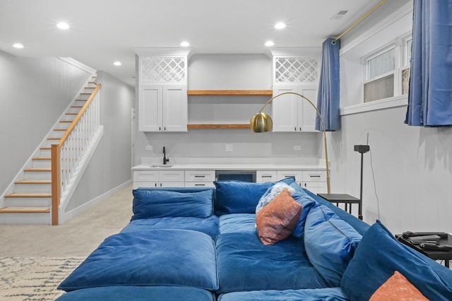 living area featuring baseboards, light colored carpet, stairs, indoor wet bar, and recessed lighting