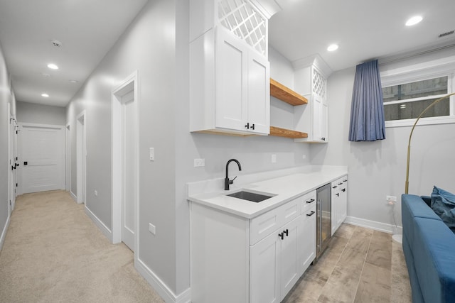 kitchen with recessed lighting, open shelves, white cabinetry, and a sink