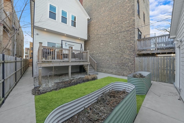 back of property featuring a wooden deck, a lawn, and a fenced backyard