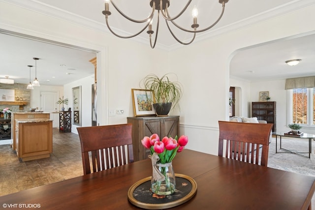 dining space featuring arched walkways, an inviting chandelier, and crown molding