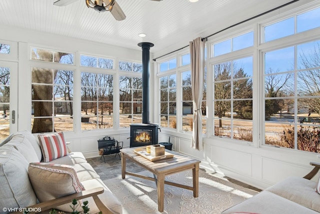 sunroom featuring ceiling fan and a wood stove