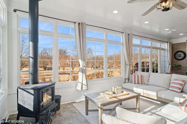 sunroom featuring a wood stove and a ceiling fan