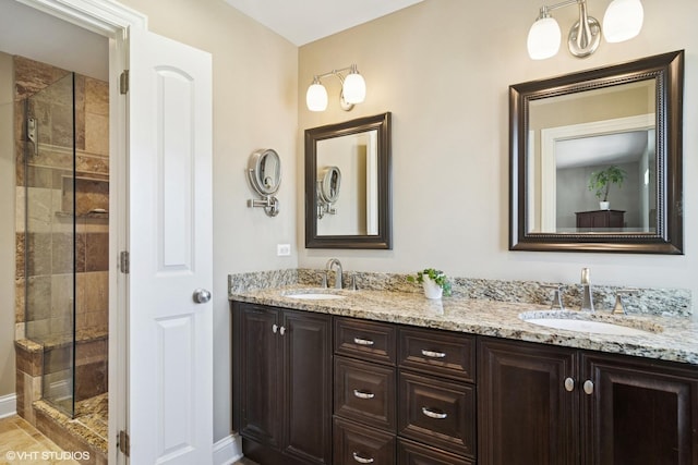 bathroom featuring double vanity, a shower stall, and a sink