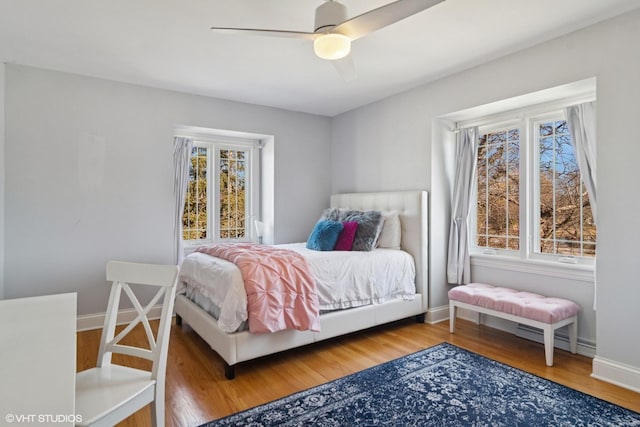 bedroom featuring baseboards, wood finished floors, and a ceiling fan