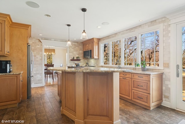 kitchen with dark wood-style floors, a center island, freestanding refrigerator, light stone countertops, and a chandelier