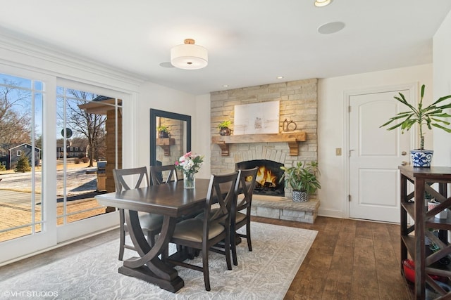 dining space featuring recessed lighting, baseboards, a stone fireplace, and hardwood / wood-style flooring