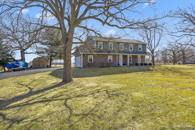 colonial inspired home featuring aphalt driveway, brick siding, covered porch, and a front lawn