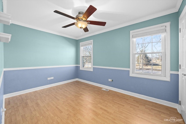 empty room featuring baseboards, wood finished floors, visible vents, and ornamental molding