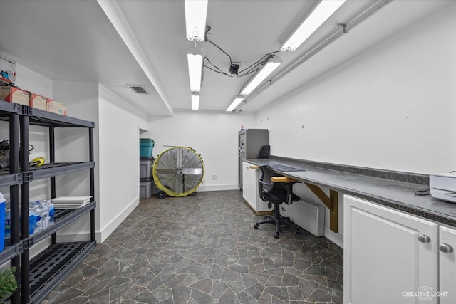 office featuring visible vents, baseboards, and stone finish floor