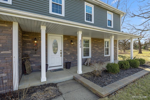 doorway to property with a porch and stone siding