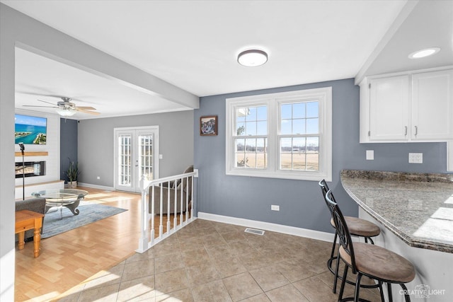 kitchen featuring baseboards, white cabinetry, a breakfast bar area, and a fireplace