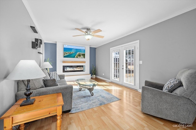 living area with crown molding, baseboards, french doors, a fireplace, and wood finished floors