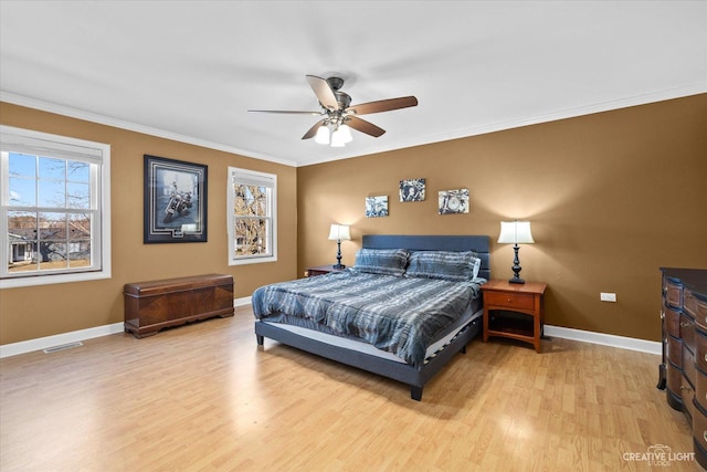 bedroom featuring visible vents, ornamental molding, a ceiling fan, wood finished floors, and baseboards