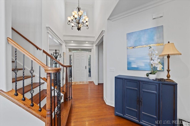 entrance foyer featuring ornamental molding, dark wood-style floors, stairway, baseboards, and a chandelier