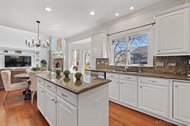 kitchen featuring stainless steel dishwasher, light wood-style flooring, a kitchen island, and a sink