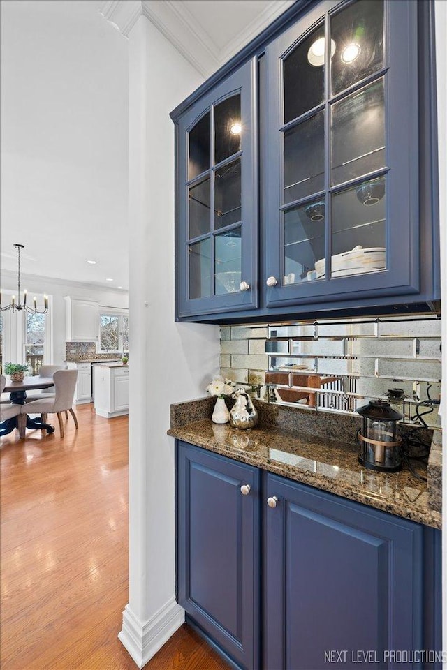 bar featuring tasteful backsplash, crown molding, and wood finished floors