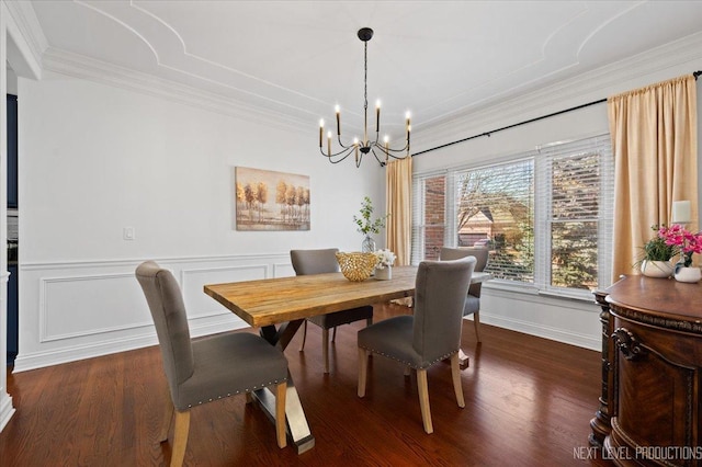 dining space with a wainscoted wall, a notable chandelier, dark wood-style floors, crown molding, and a decorative wall