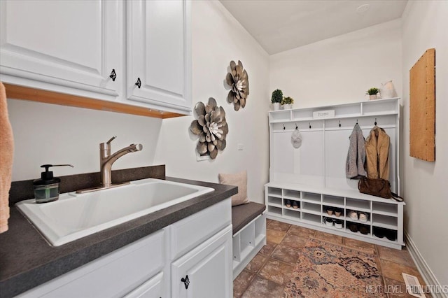 mudroom featuring stone finish flooring, baseboards, and a sink