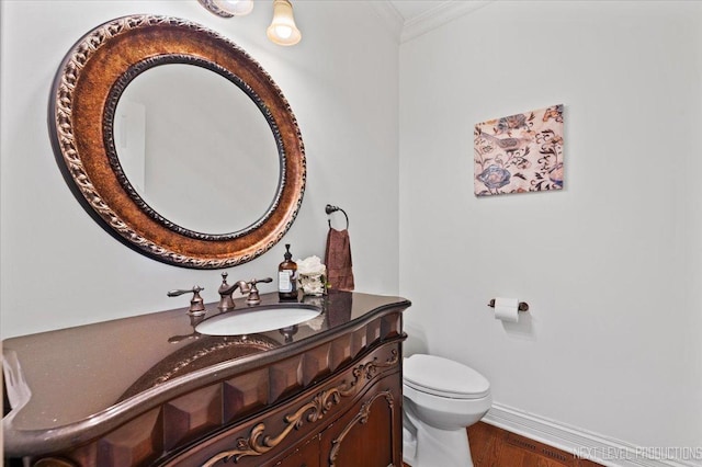 bathroom with baseboards, toilet, ornamental molding, wood finished floors, and vanity