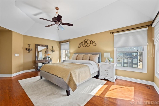 bedroom with visible vents, multiple windows, lofted ceiling, and wood finished floors