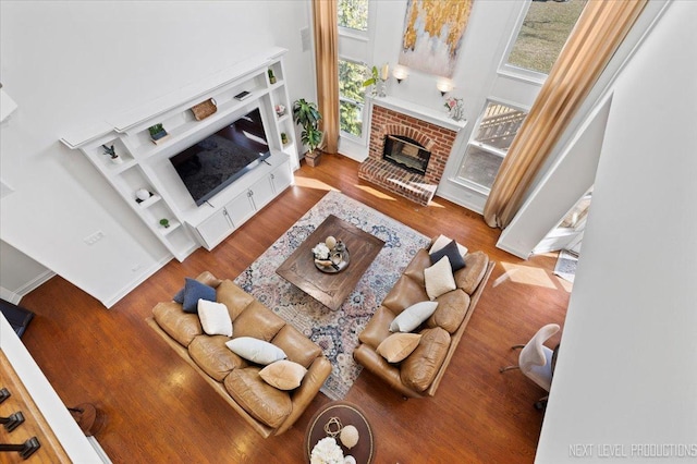 living room featuring built in features, heating unit, wood finished floors, a high ceiling, and a fireplace