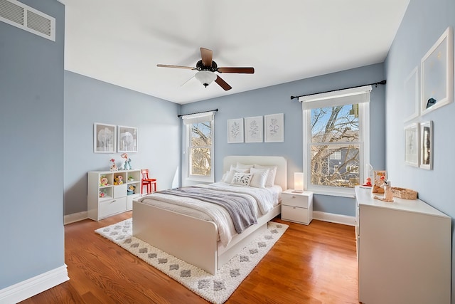 bedroom featuring ceiling fan, baseboards, visible vents, and light wood-type flooring