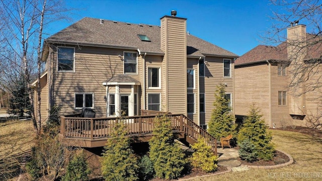 back of property featuring a wooden deck, a chimney, and a shingled roof