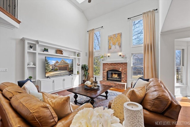 living area featuring high vaulted ceiling, a brick fireplace, and wood finished floors