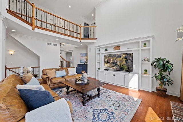 living area featuring visible vents, ornamental molding, recessed lighting, a towering ceiling, and wood finished floors