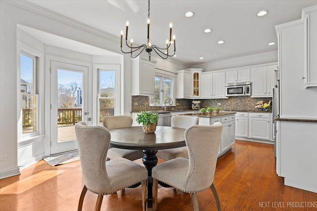 dining area featuring a chandelier, recessed lighting, crown molding, and wood finished floors