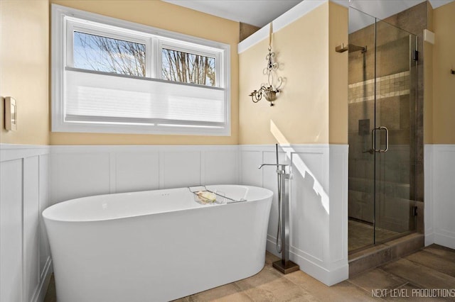 bathroom with a soaking tub, wainscoting, and a stall shower