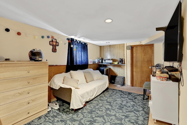 bedroom featuring wooden walls, light colored carpet, and wainscoting