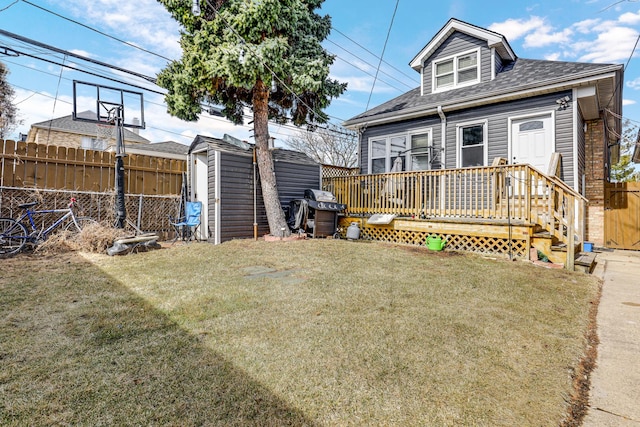 back of property with a storage shed, an outbuilding, a lawn, and fence