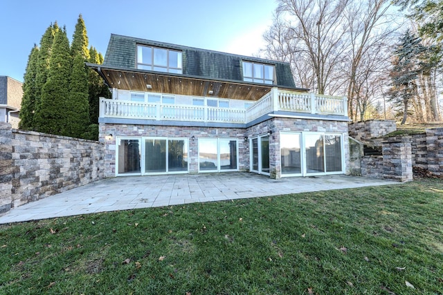 rear view of house featuring a yard, mansard roof, a balcony, and a patio