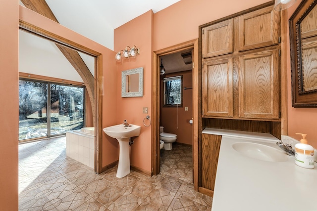 full bath featuring tiled bath, plenty of natural light, toilet, and baseboards