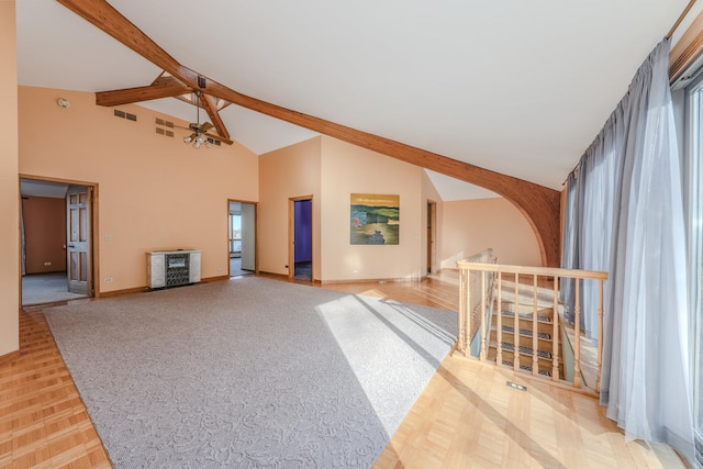 living area with beam ceiling, visible vents, high vaulted ceiling, and baseboards