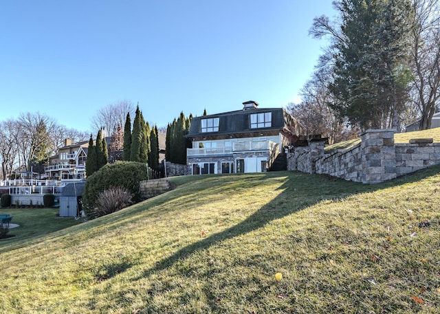 rear view of property featuring a lawn and a balcony