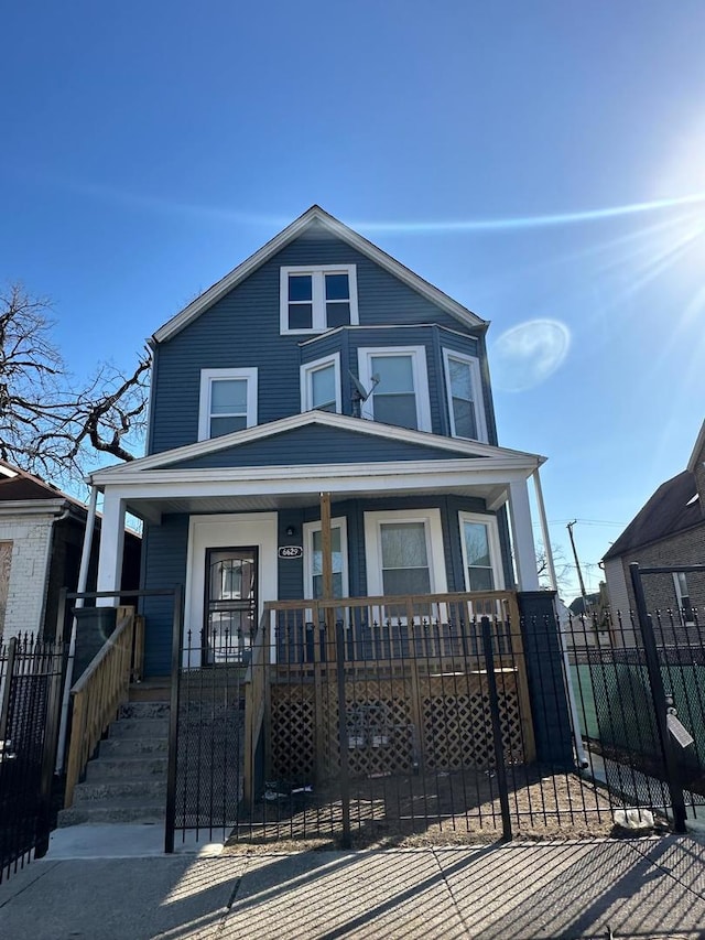 american foursquare style home featuring a porch and fence