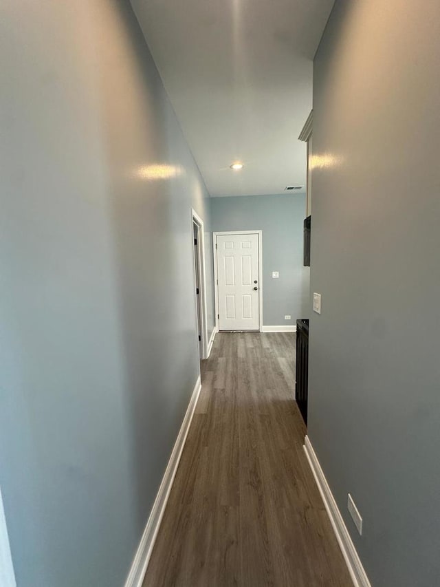 hall featuring visible vents, baseboards, and dark wood-style flooring