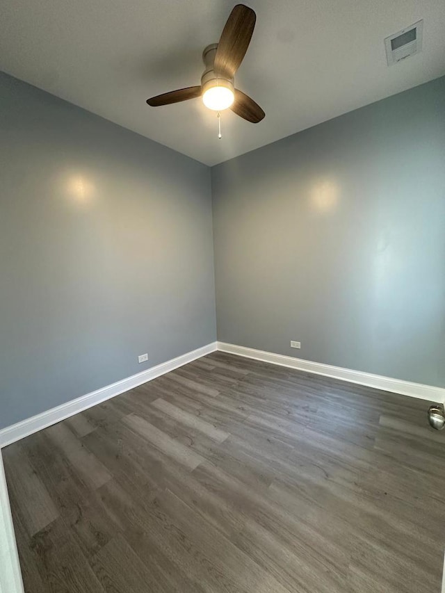 spare room with dark wood-style floors, visible vents, a ceiling fan, and baseboards