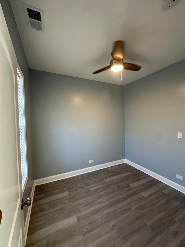 empty room with dark wood-style floors, visible vents, and baseboards