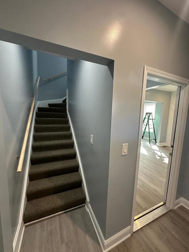 staircase featuring baseboards and wood finished floors